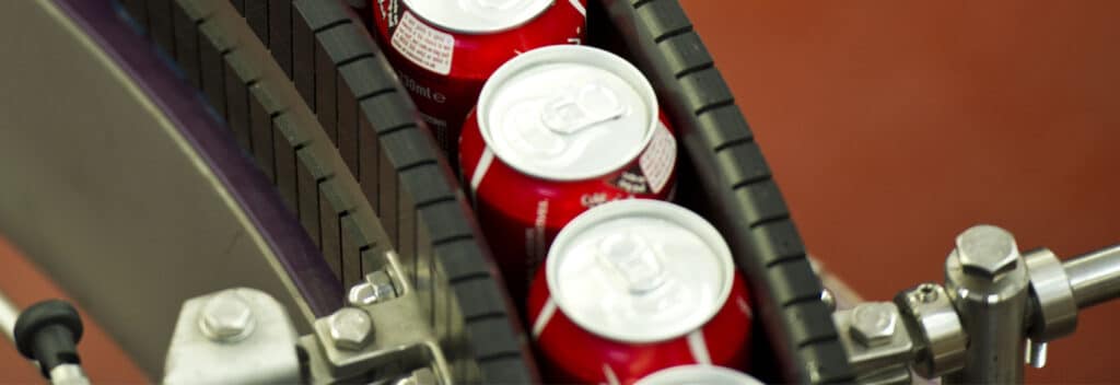 A close up of a production line with tinned drinks travelling along the conveyer belt