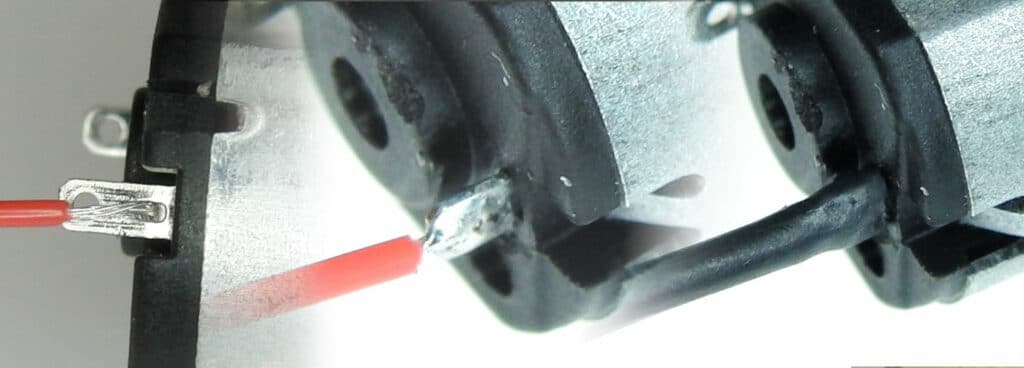 Close-up of the back of a vibration motor where adhesive, potting compound or hot-melt has been used to mechanically secure the leads (including a portion of insulation) to the PCB.