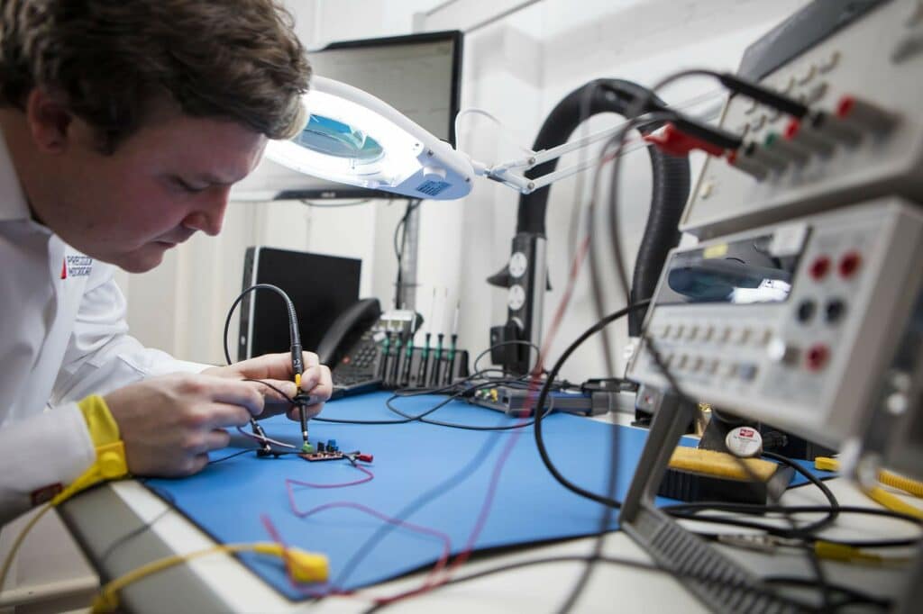 Precision Microdrives engineer using a digital desktop multimeter to test a motor