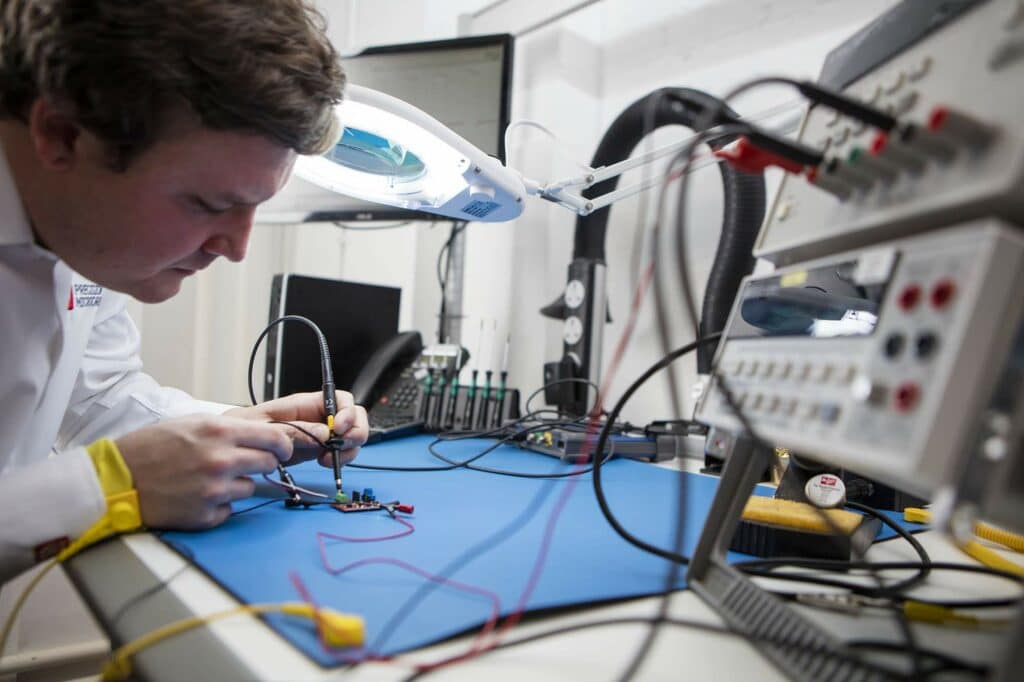 Precision Microdrives engineer using a digital desktop multimeter to test a motor 