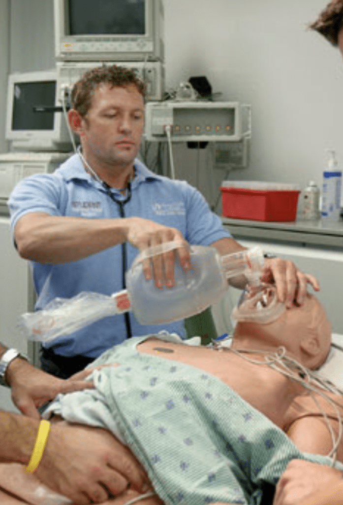 A medical profession practicing CPR on a patient simulator dummy.