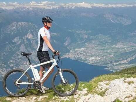 A cyclist stood on a mountain ridge with an e-bike.