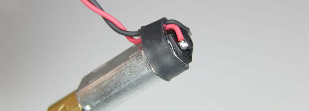 A vibration motor with a band of self-adhesive heatshrink used to pin the leads to the motor casing