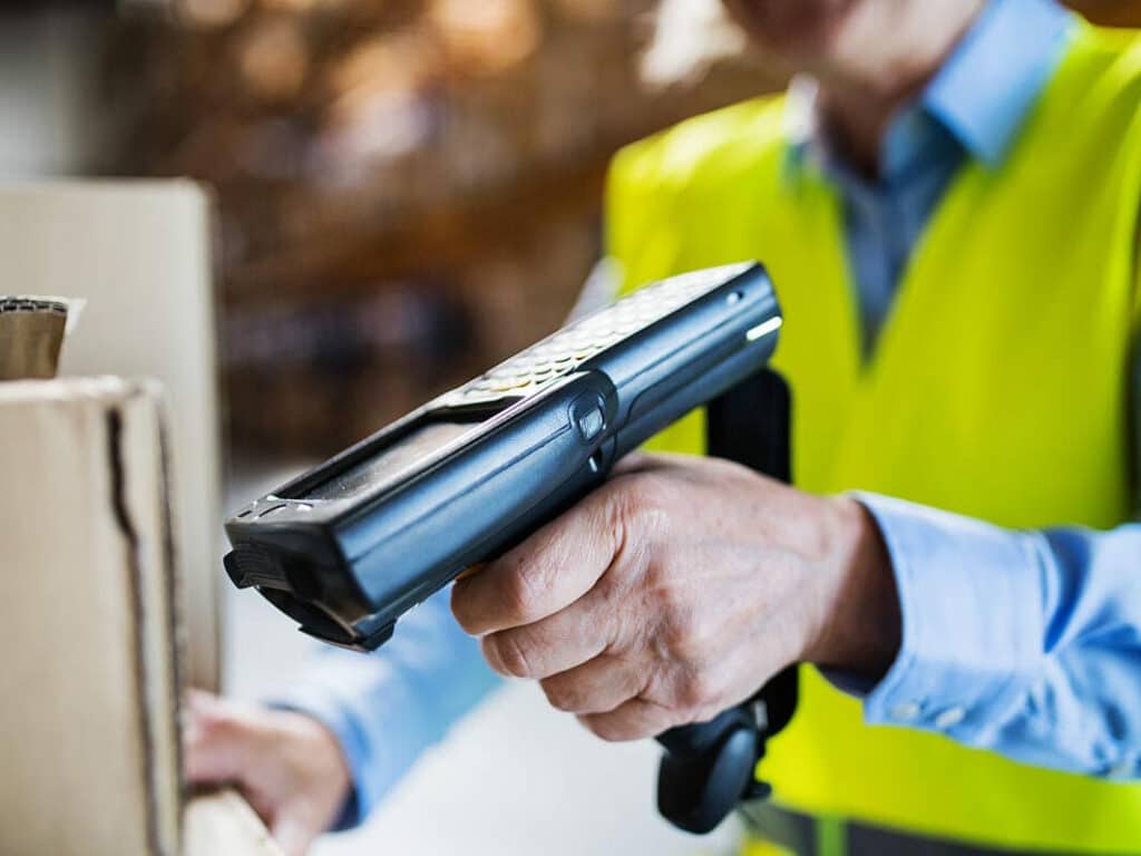 A person using a handheld barcode scanner to scan a barcode on a box