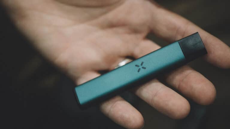 The palm of a hand with a slim vape laying across the fingers