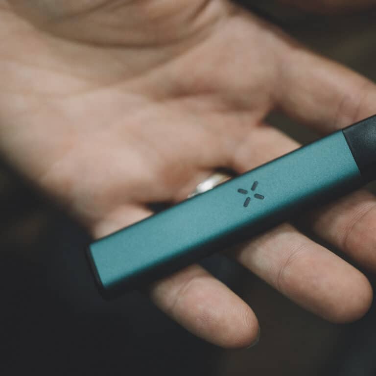 The palm of a hand with a slim vape laying across the fingers