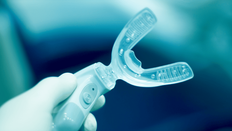 A hand holding an orthodontic tooth re-aligning device