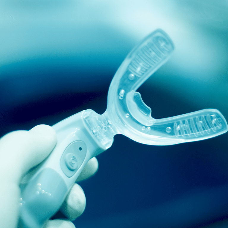 A hand holding an orthodontic tooth re-aligning device